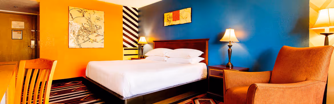 Colorful Artist guestroom with mural on the wall with king bed with white bedding