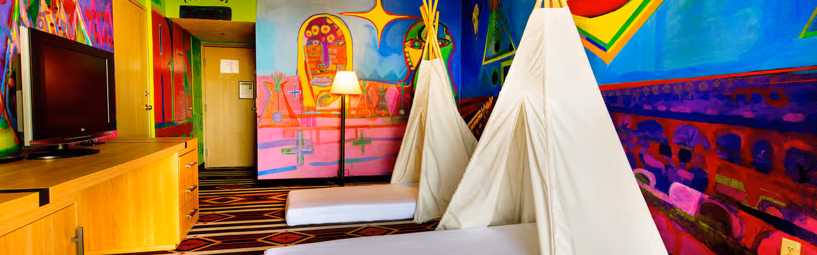 Colorful Artist guestroom with mural on the wall with two teepes over beds for children