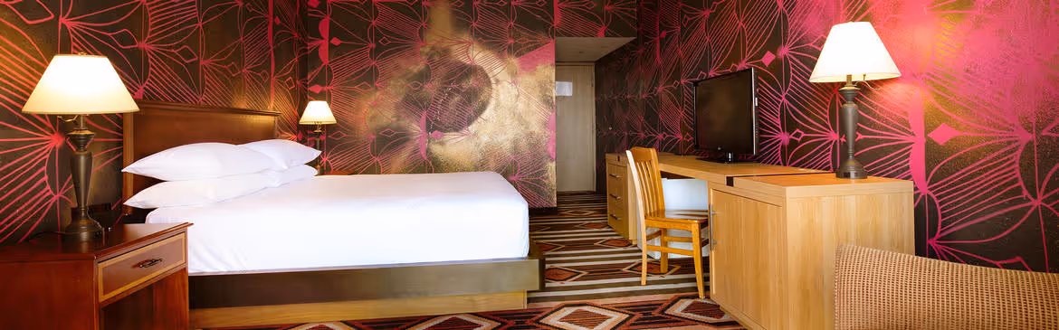 Colorful Artist guestroom with mural on the wall with king bed with white bedding