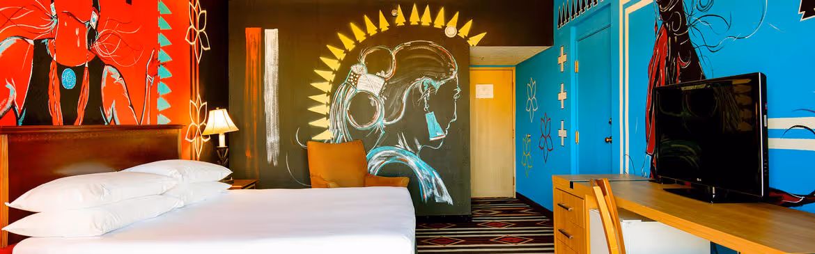 Colorful Artist guestroom with mural on the wall with king bed with white bedding
