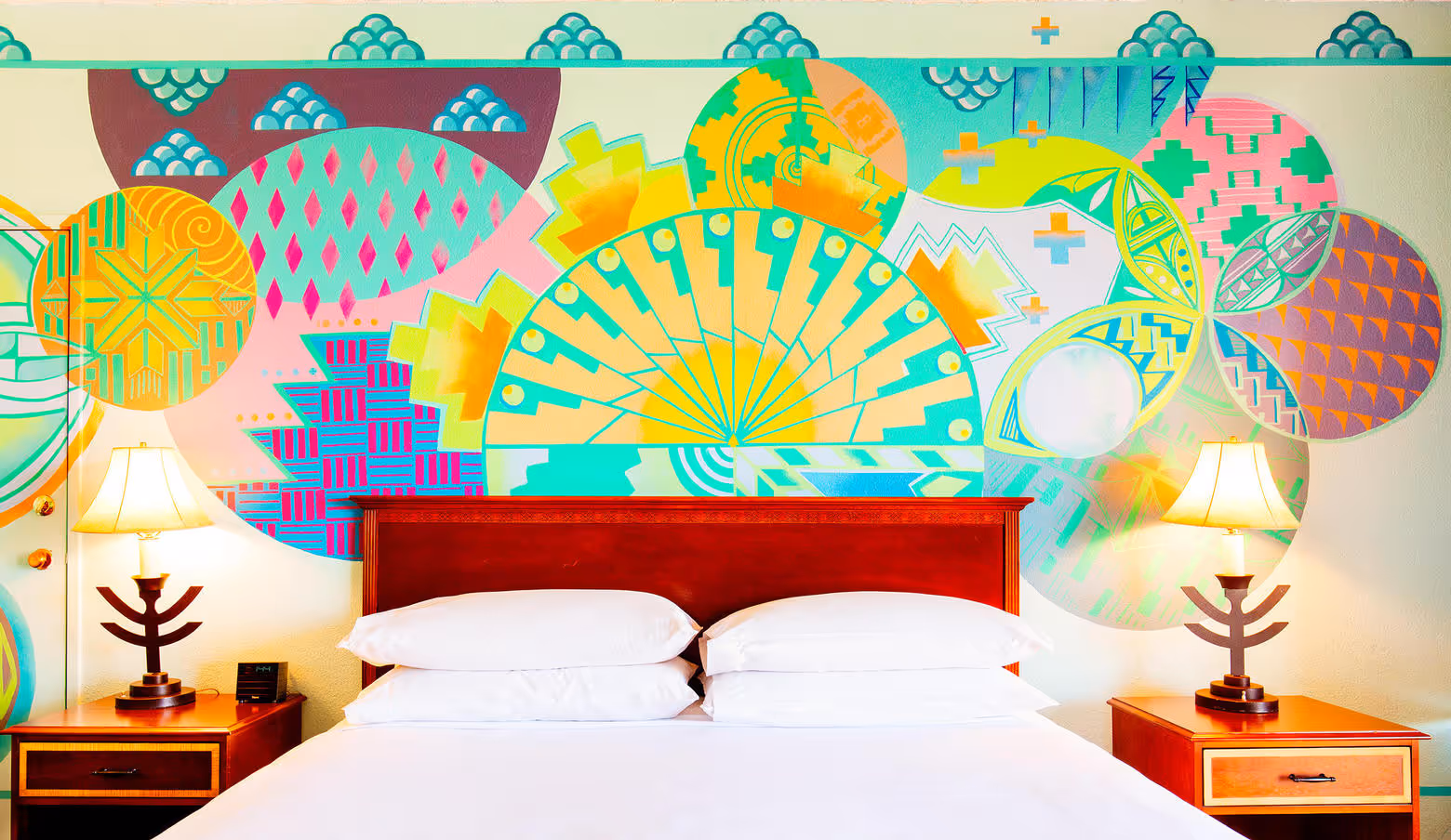 Wall of artist guestroom with king bed and brightly colored mural behind