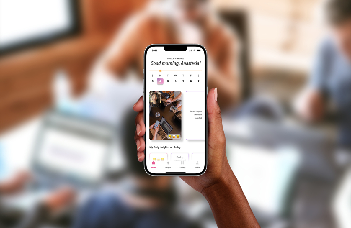 A blurry background with a woman's hand in the forefront holding up an IPhone 13 in her right hand with the MIRROR App open.