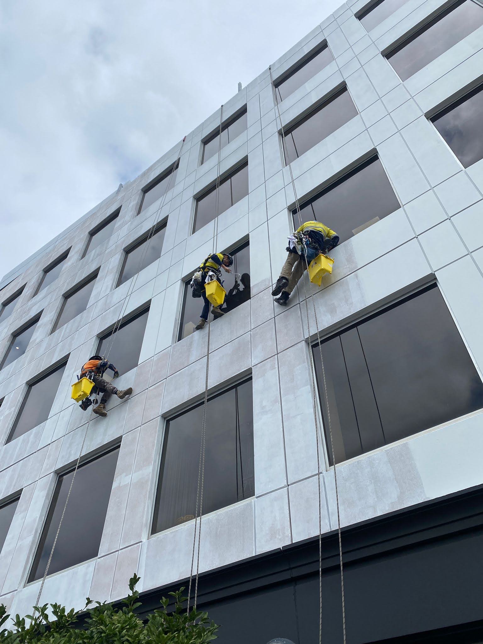 IRATA certified rope access painter repainting a commercial building facade in Melbourne