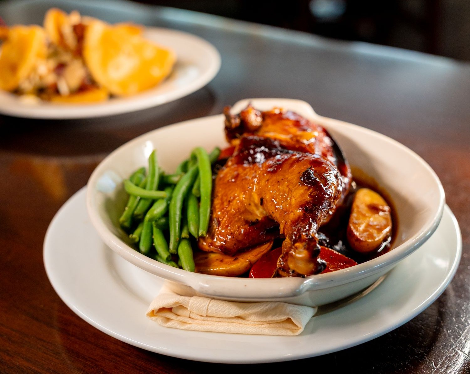 Dish of half roasted chicken with green beans on a table