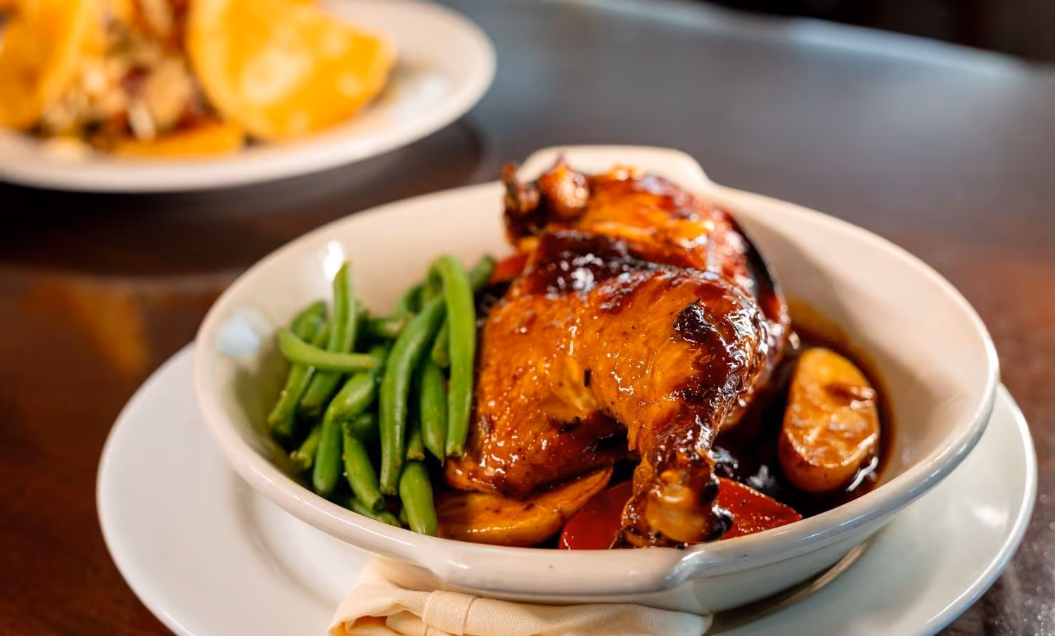 Dish of half roasted chicken with green beans on a table