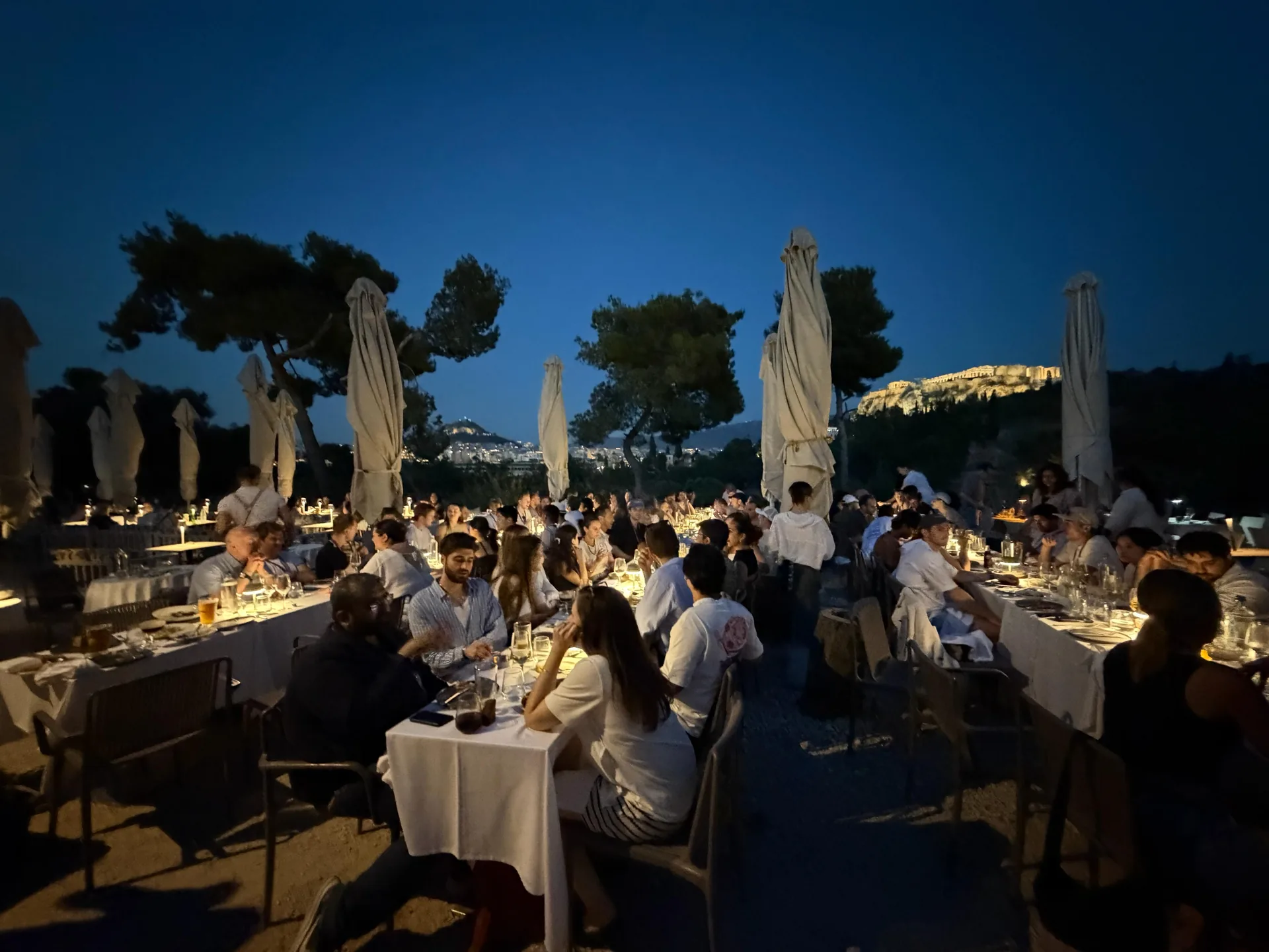 Entrepreneur First's Global Summit dinner under string lights at blue hour in Athens