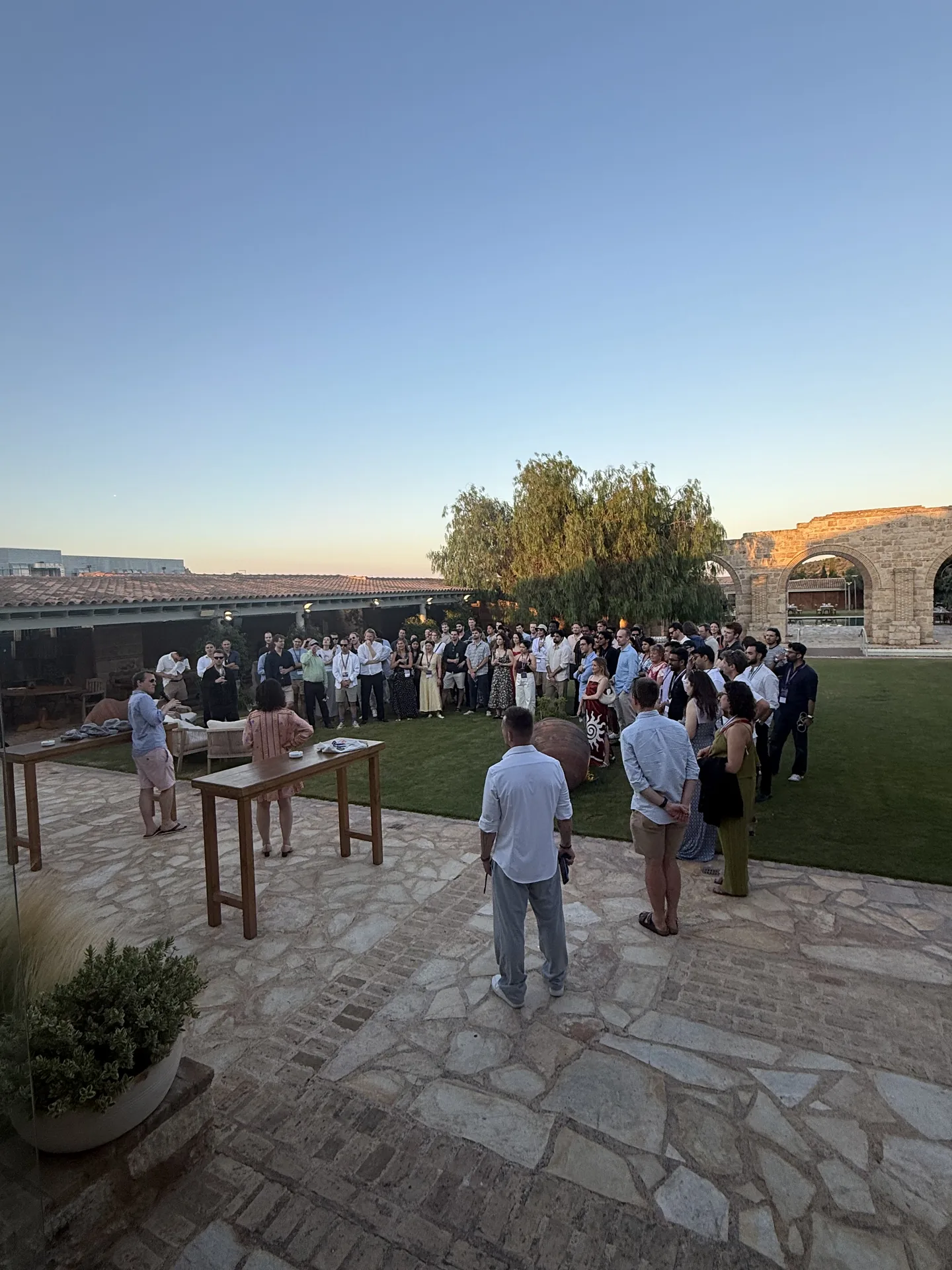 Guests dressed in white and gold gathering on a stone terrace at dusk