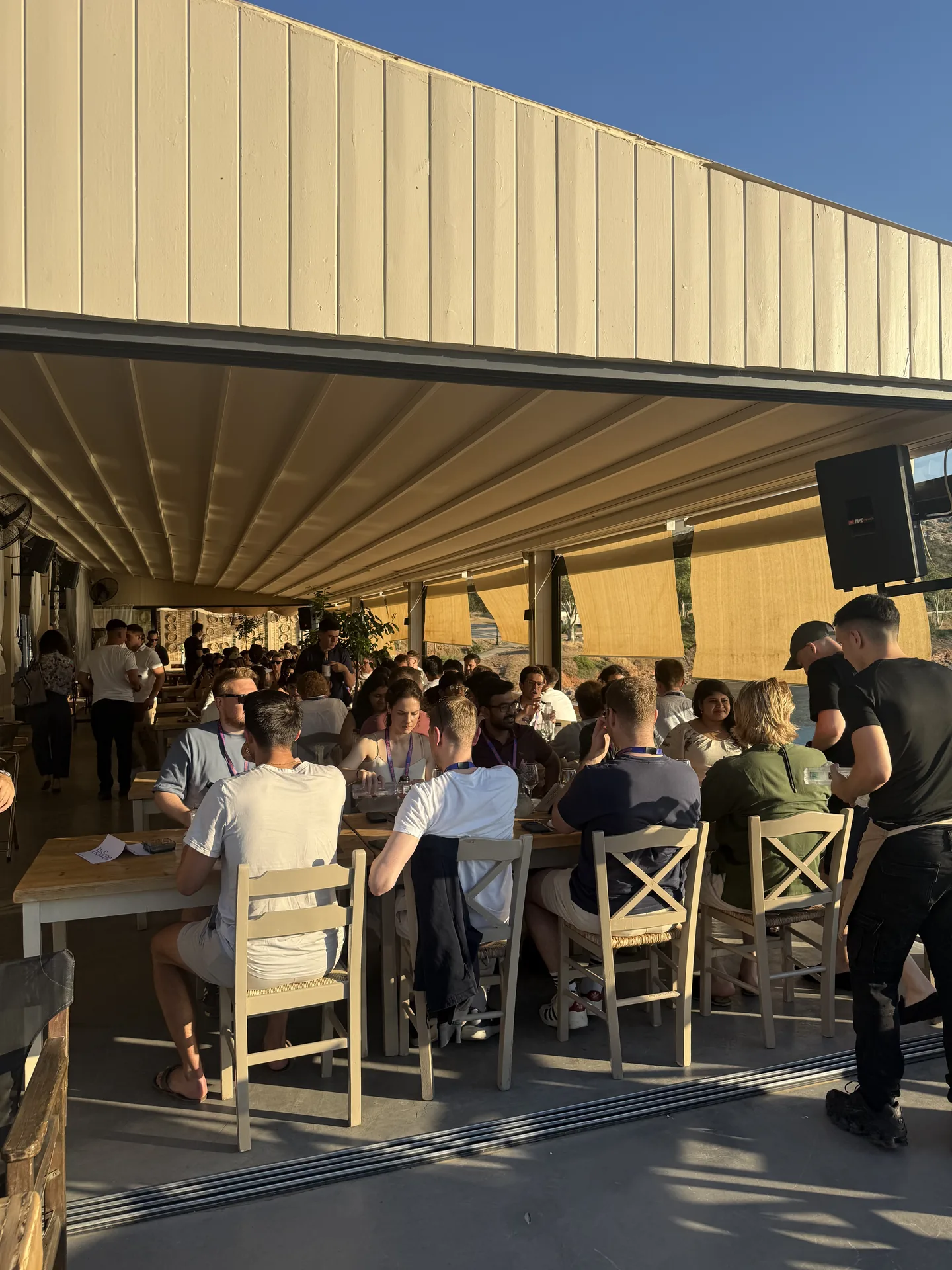 Attendees seated at a covered evening dinner with a speaker and AV setup