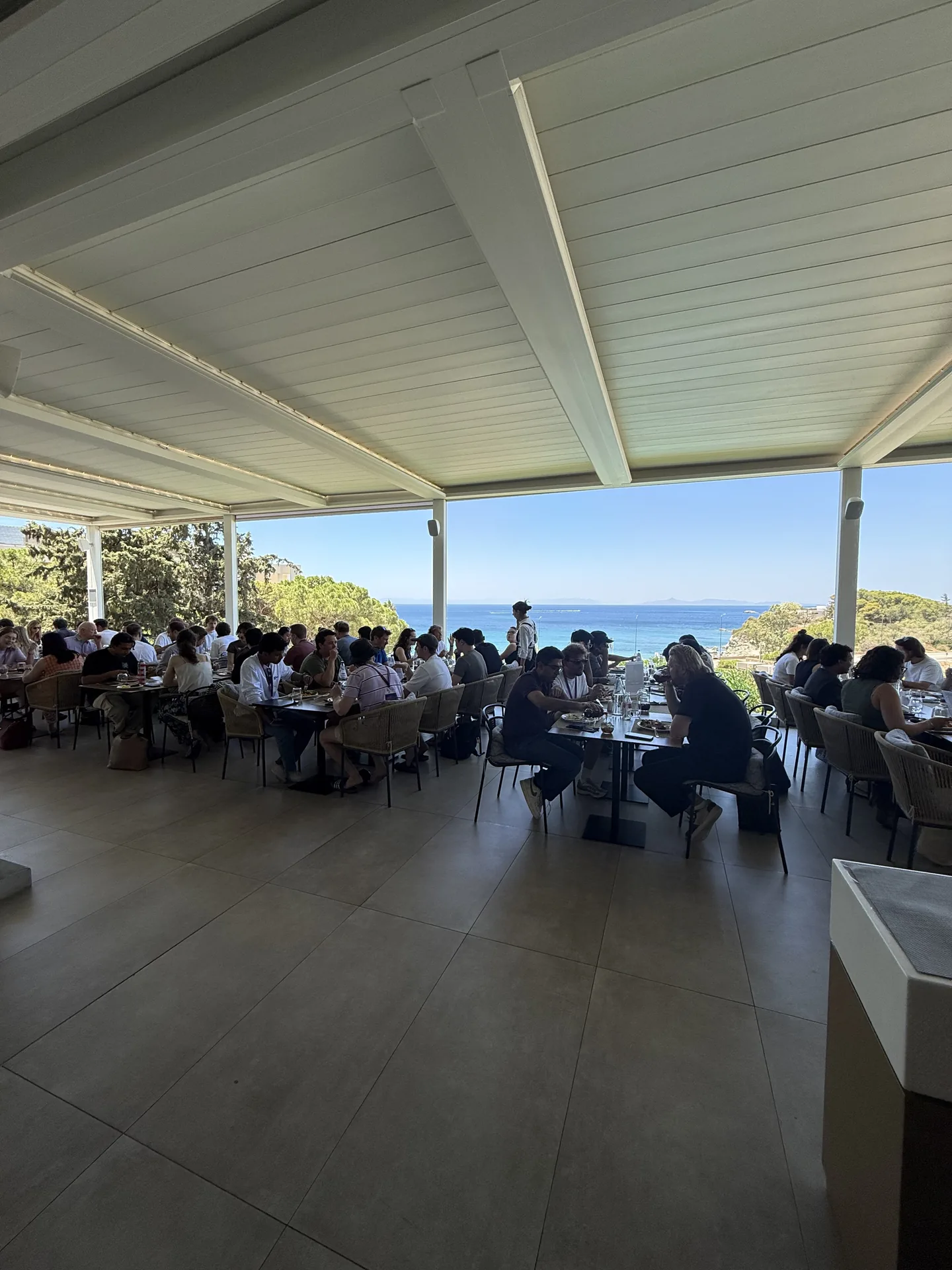 Attendees dining on a covered terrace overlooking the sea