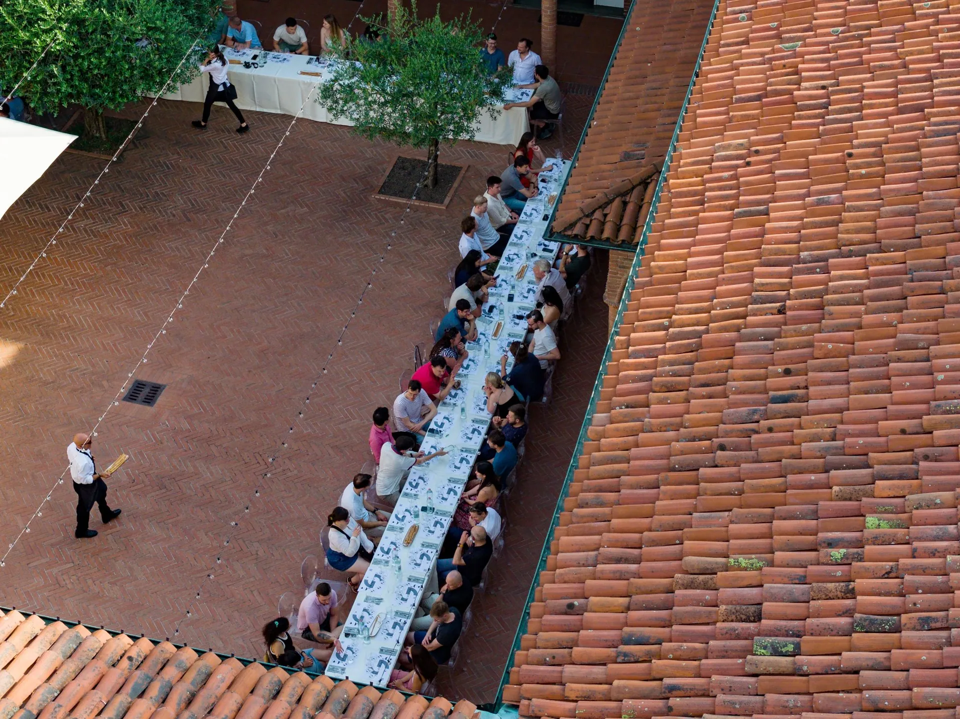 A long communal dinner table in a courtyard at golden hour