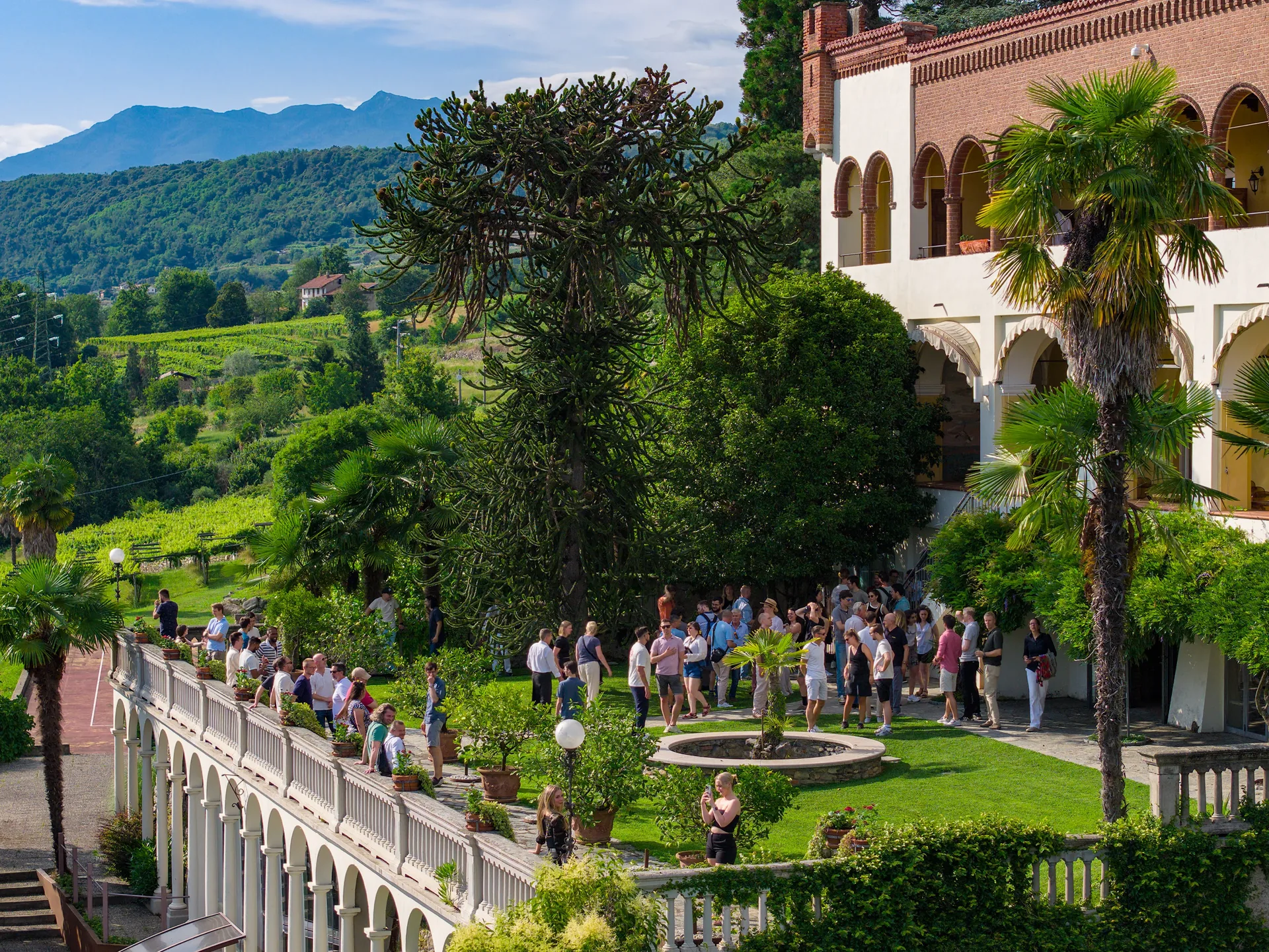 OnsiteHub retreat guests gathered in the gardens of a historic Italian villa with vineyards and mountains beyond