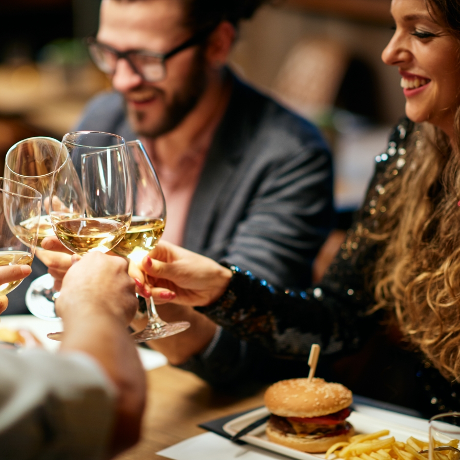 Stockbild von Freunden, die im Restaurant mit Weingläsern anstoßen.