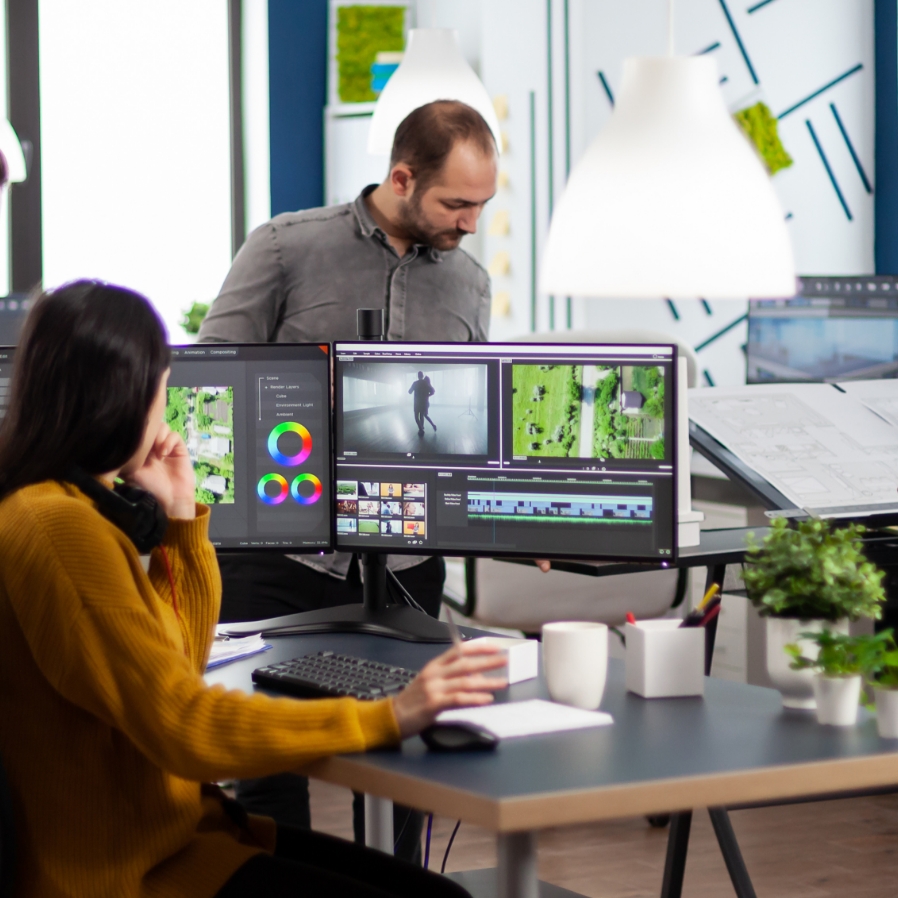 Stockbild eines Startups mit Fokus auf einer Mitarbeiterin, welche an einem Videoprojekt sitzt