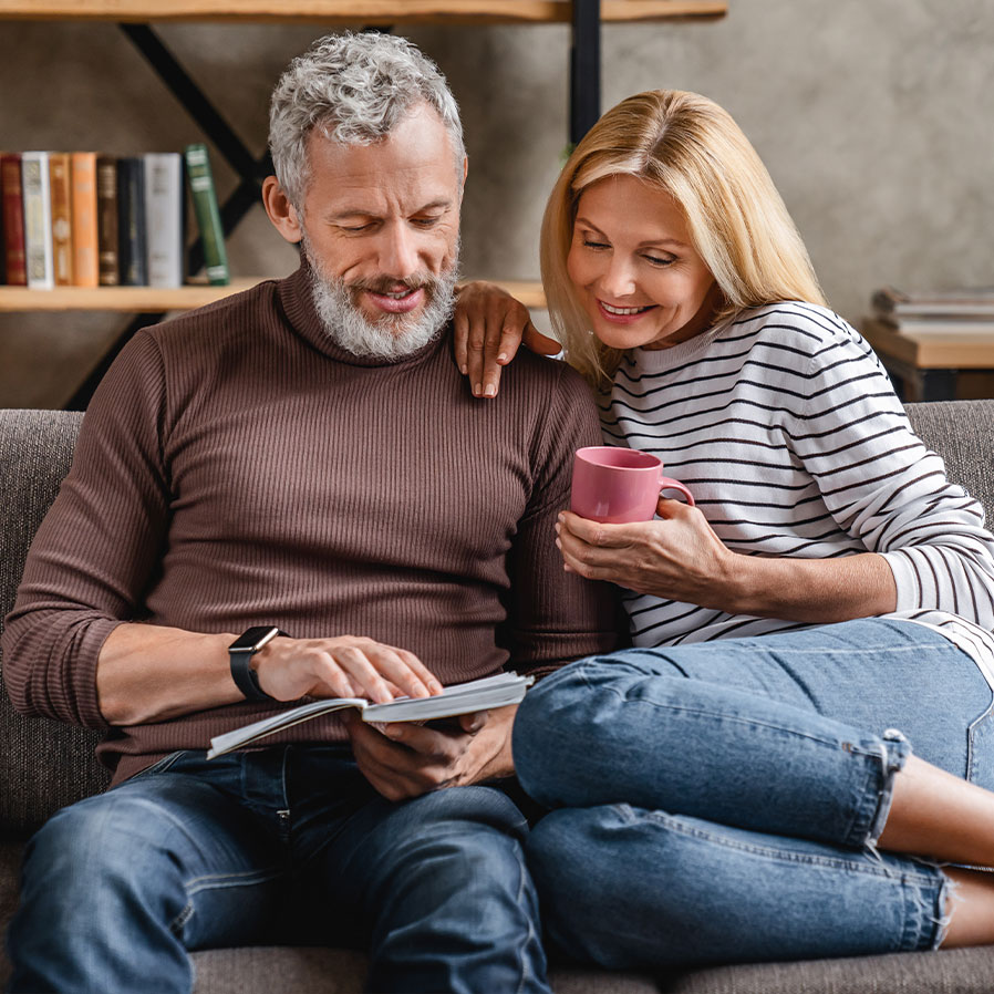 Stockbild einer jungen Mutter mit ihrem Sohn auf der Wohnzimmercouch beim Vorlesen