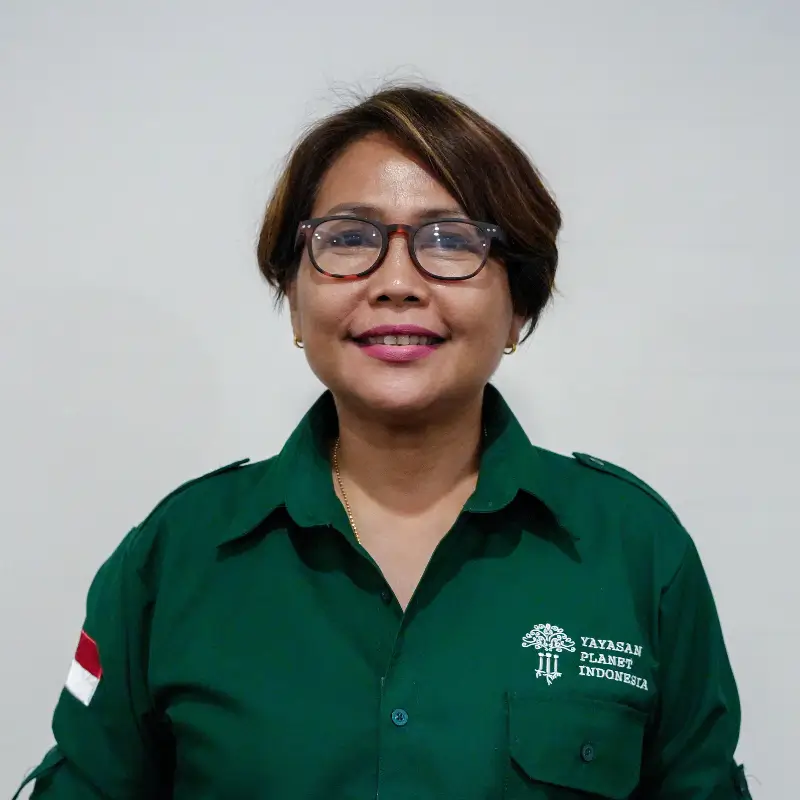 Novia Sagita, an asian brunettte with short hair wearing square glasses, light pink lipstick and a button up green shirt with the Yayasan Planet Indonesia logo on it
