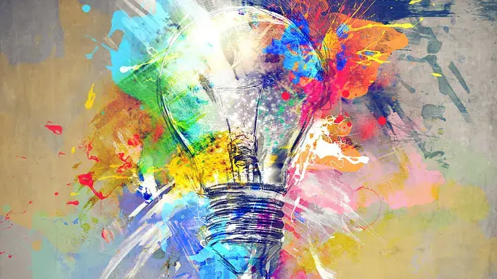 A lightbulb with splashes of colored paint surronding it.