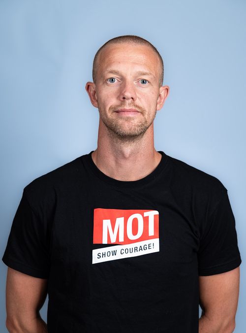 mann i svart t-skjorte ser i kamera