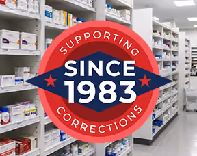 A graphic over pharmacy shelving that reads "Supporting Corrections, since 1983"