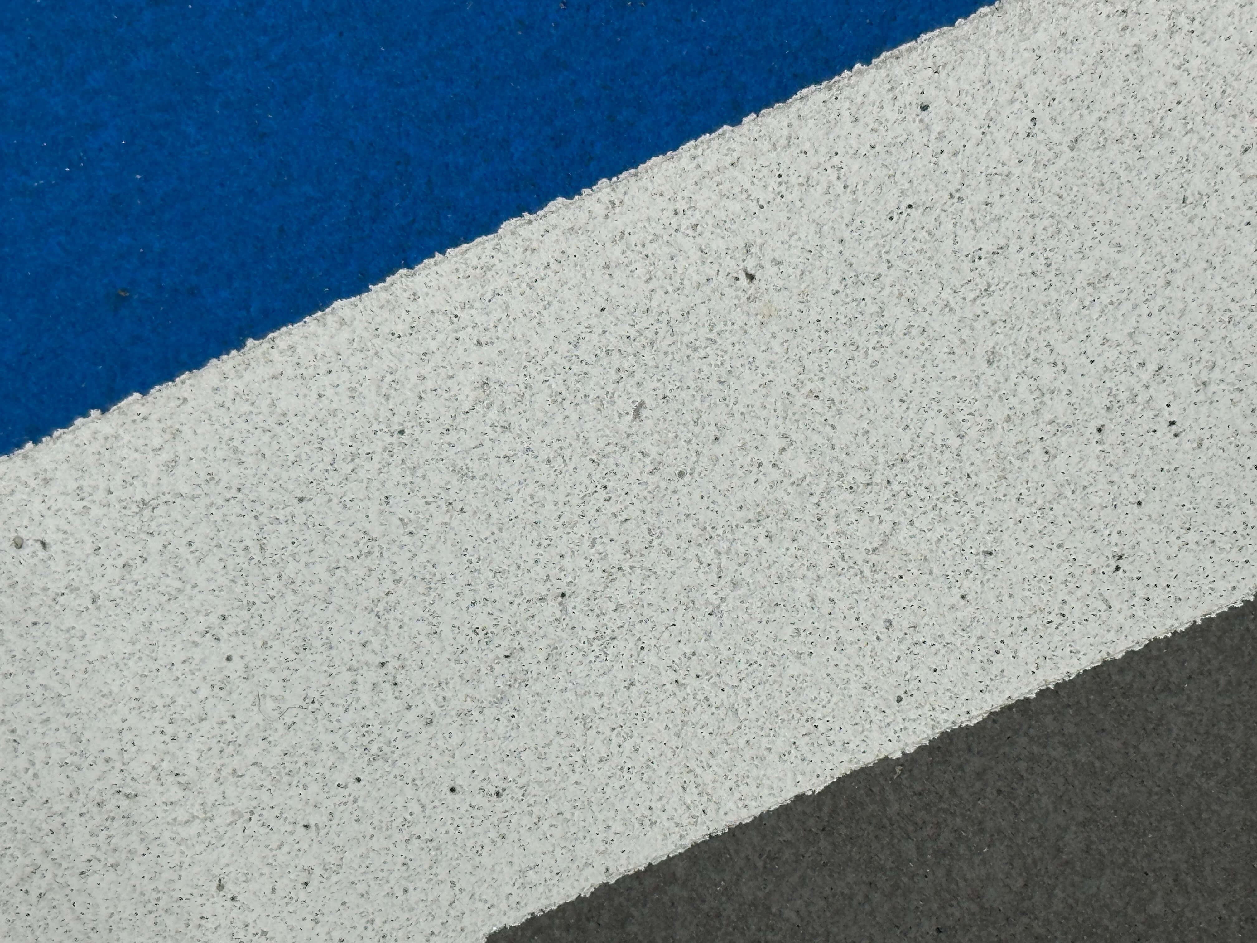 A closeup of paint on a pickleball court - you can see the grains of sand beneath the paint.