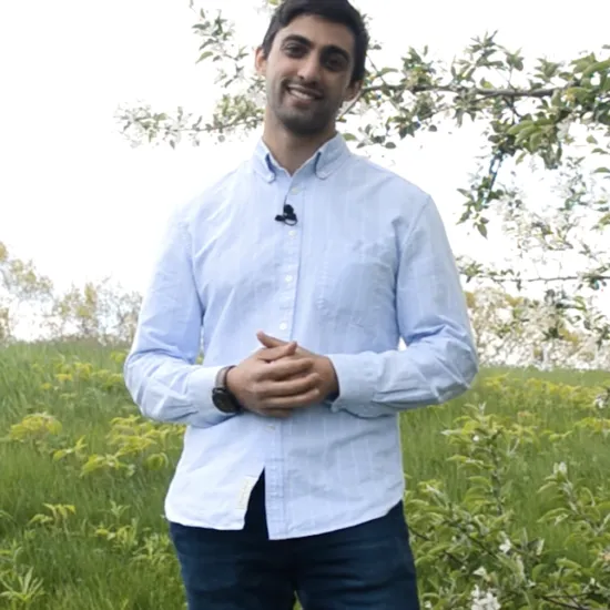Jacob Suissa stands in a field of grass and flowers. A screenshot from the Let's Botanize video "What Is a Flower?"