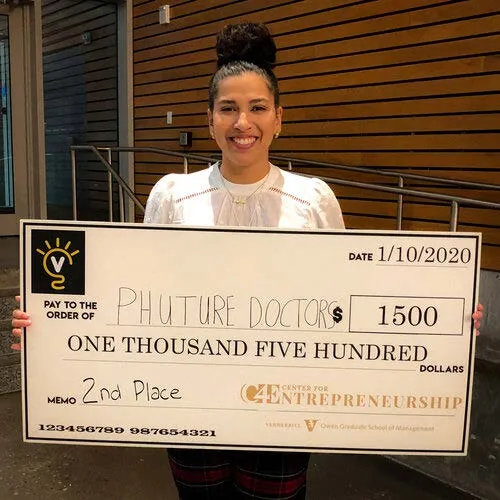 A woman poses for the camera and holds a check for $1,500.