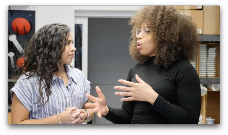 Two brown-haired women face each other in conversation.
