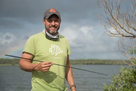 A man in a green t-shirt standing by a river