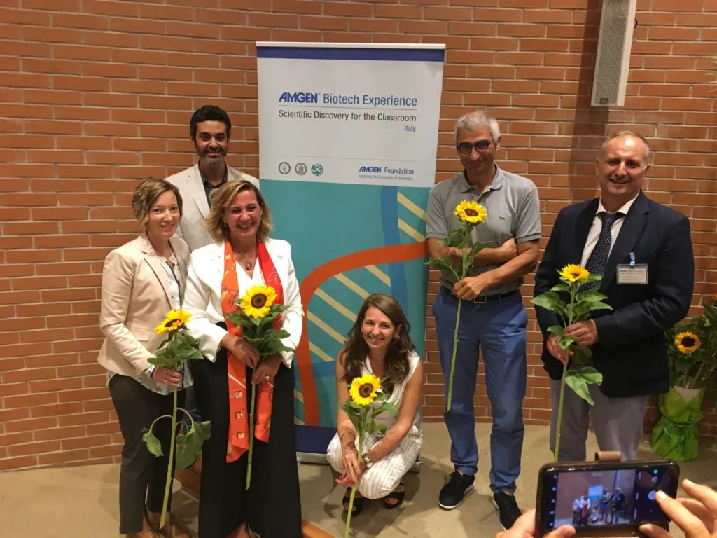 A group of ABE Italy educators and administrators pose for a photo holding sunflowers. 