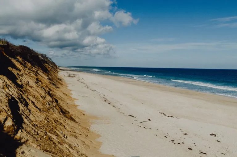 A sandy ocean beach next to a steep cliff.
