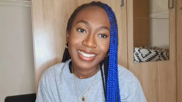 A smiling woman with black and blue hair.