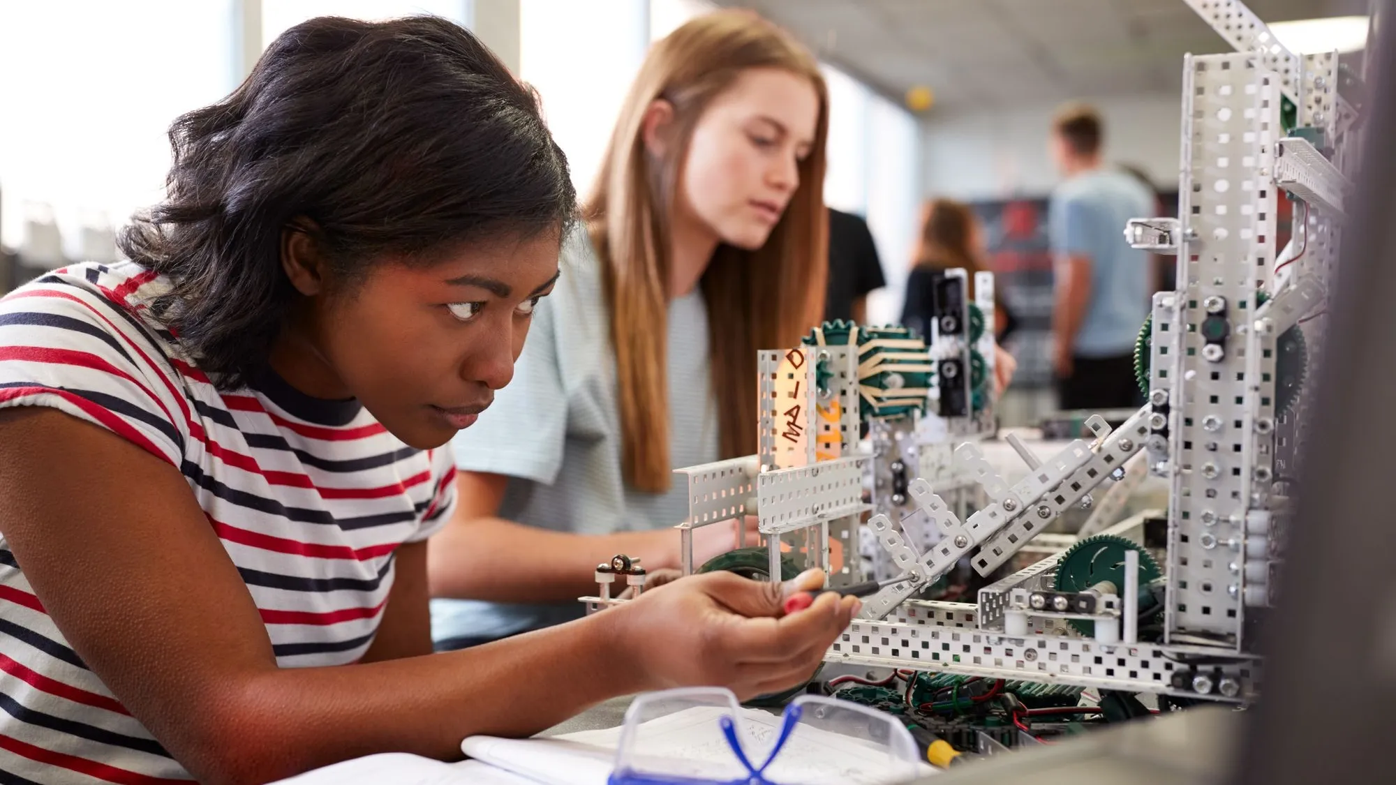 A student sits at a laboratory bench, working intently on a robotic project.
