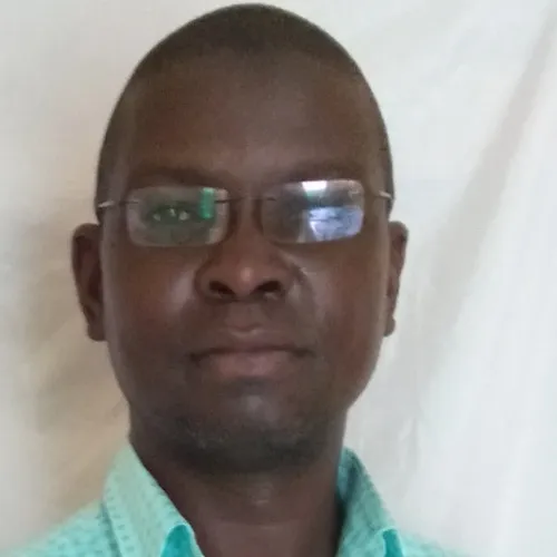A Black man with short black hair in glasses and a mint green shirt.