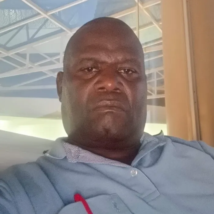 A Black man wearing a light blue polo shirt.