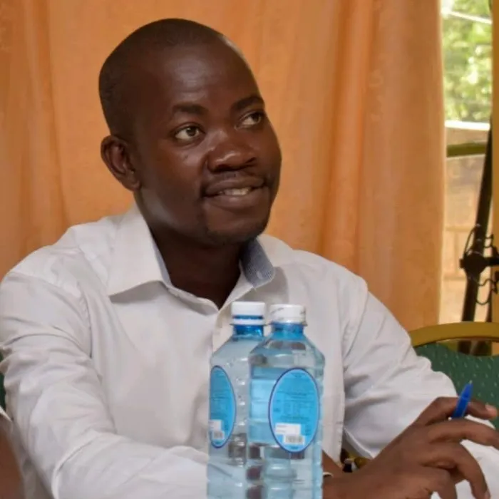 A Black man with very short hair and a short goatee wearing a white dress shirt.