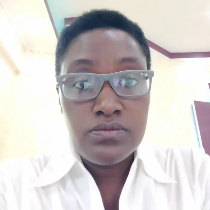A Black woman with short black hair wearing glasses and a white blouse.