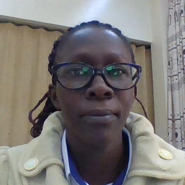 A Black woman with black hair, worn up, wearing in glasses and an off-yellow jacket..