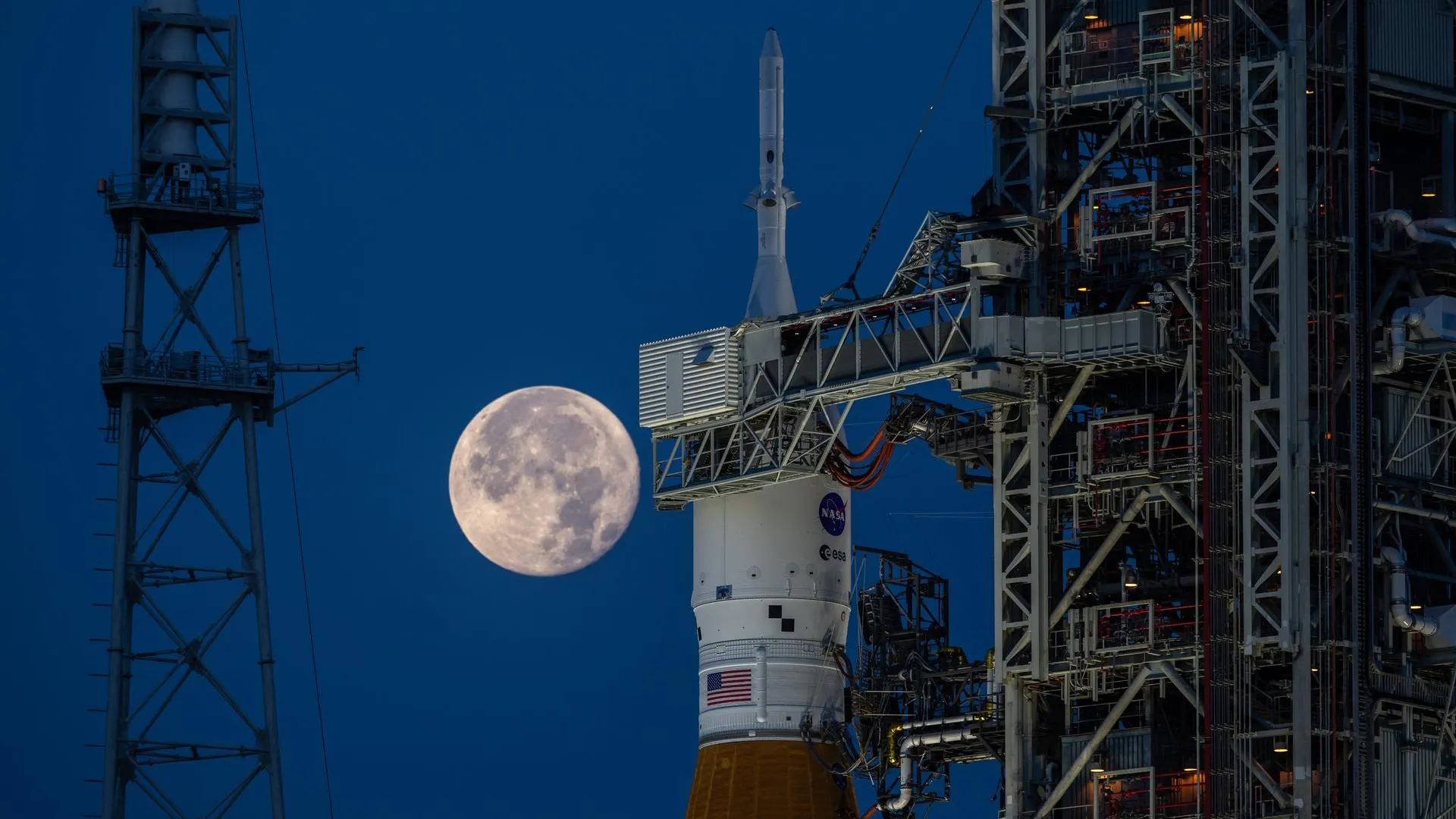 NASA's Artemis I spacecraft stands on a launchpad with the full Moon in the background. Photo by NASA/Ben Smegelsky.