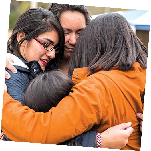 Four people in a close group hug, showing affection and support.