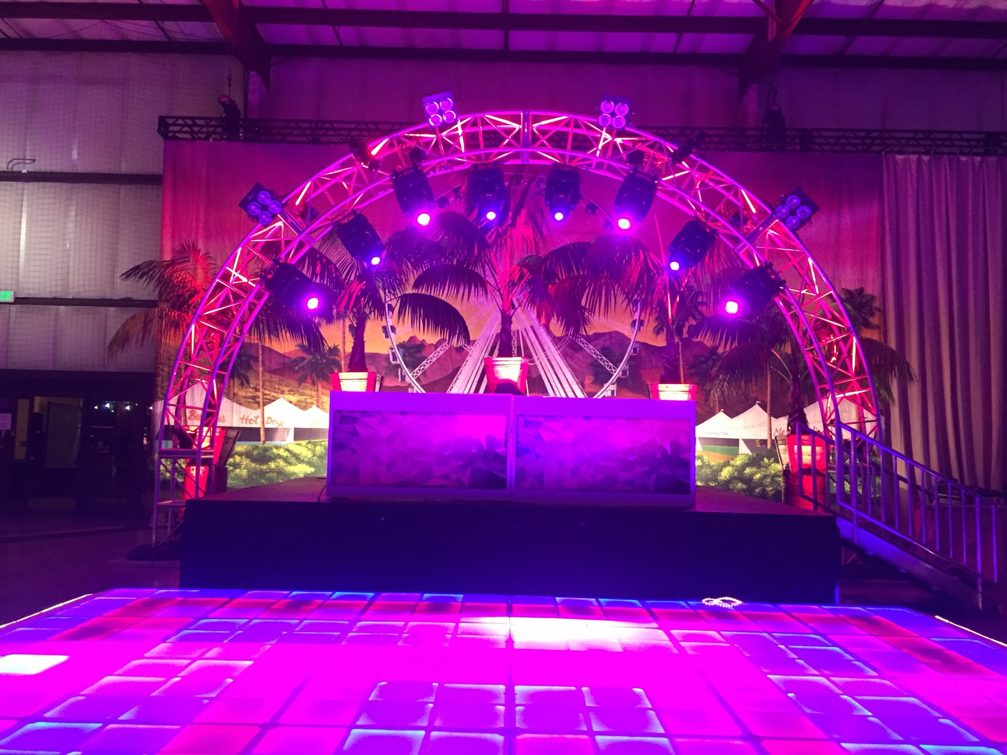 Circular truss arch with hung lighting fixtures rigged by Impact over an event stage