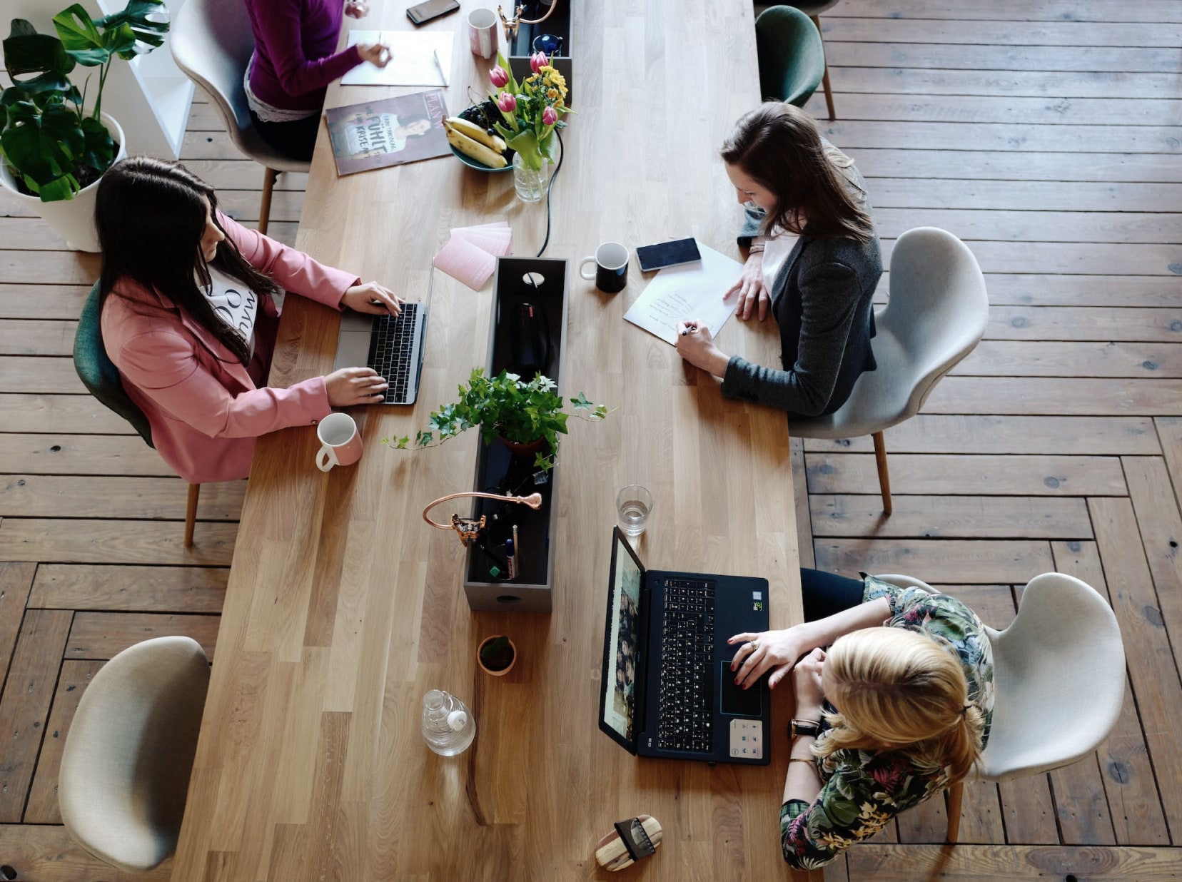 Two women sitting on laptops at a community table