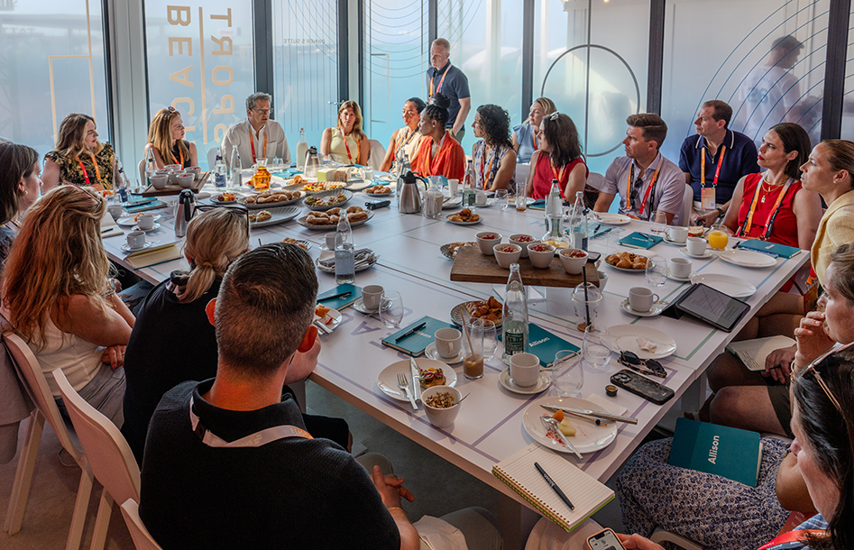 Group of people sitting around a table with food and drink