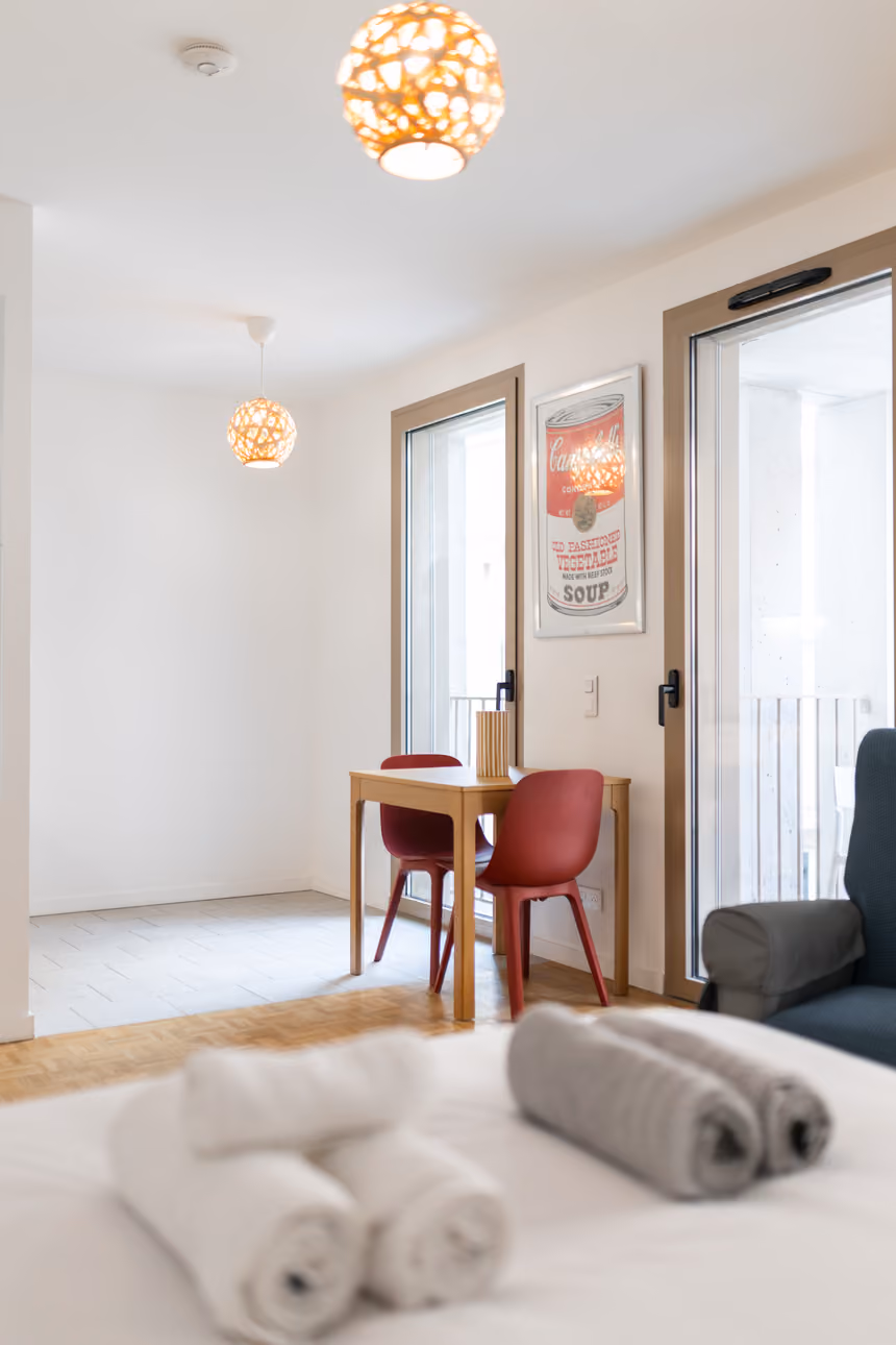 Coin repas et porte-fenêtre de la terrasse, vus depuis le lit préparé pour l'arrivée