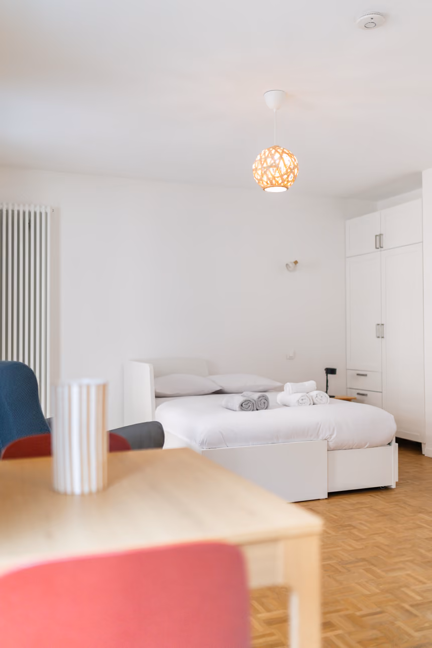 Lit et armoire de l'appartement de 29 m², vus depuis la table à manger
