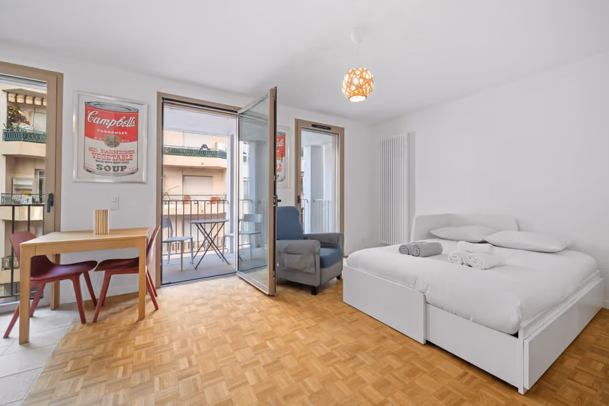 Séjour de l'appartement de 29 m² : table à manger, lit et porte-fenêtre ouvrant sur la terrasse privative