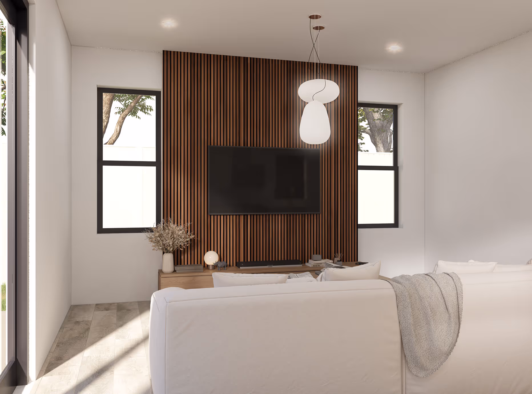 Minimalist living room with a wall-mounted TV on vertical wood paneling, white sofa, and modern pendant light fixture.