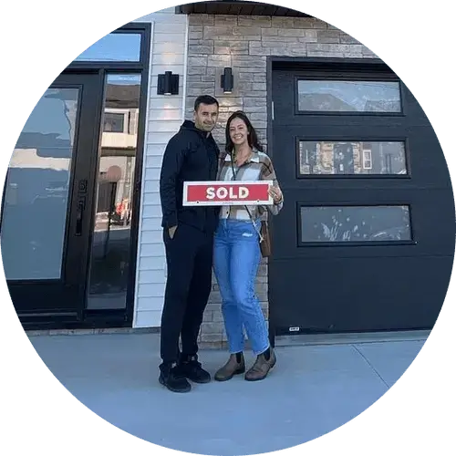 Smiling couple standing outside a modern house holding a red and white SOLD sign. Signature Home Builders in Halifax, Nova Scotia