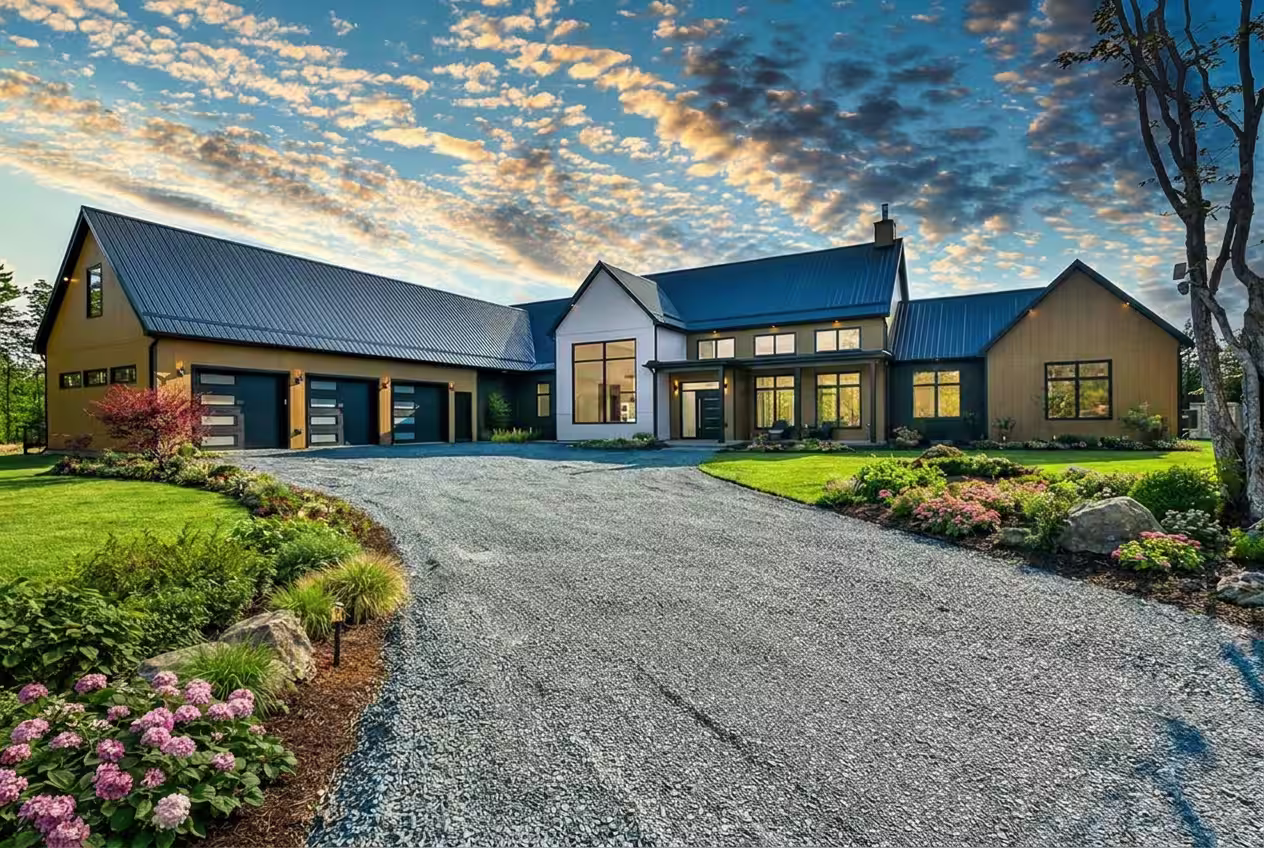 Modern large new construction house with dark metal roof, multiple garages, and landscaped garden under a cloudy sky at sunset. Built by Signature Homes.