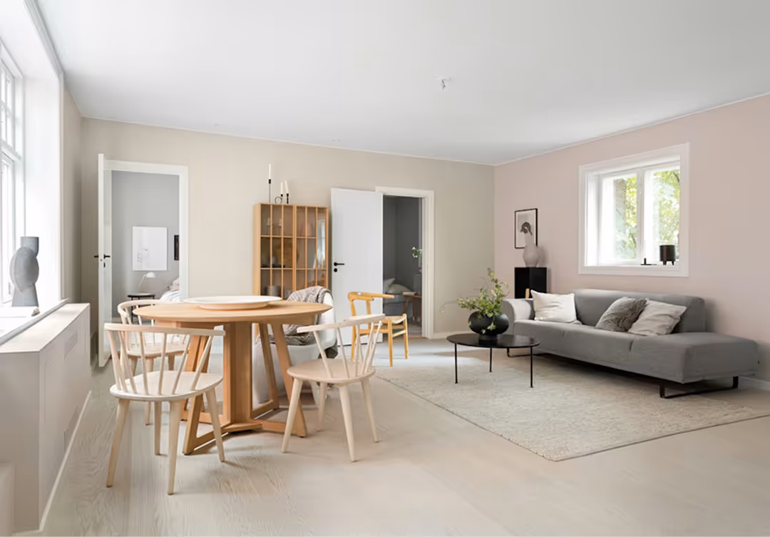 Bright open-plan living and dining area inside a secondary suite with neutral finishes, large windows, and modern furniture