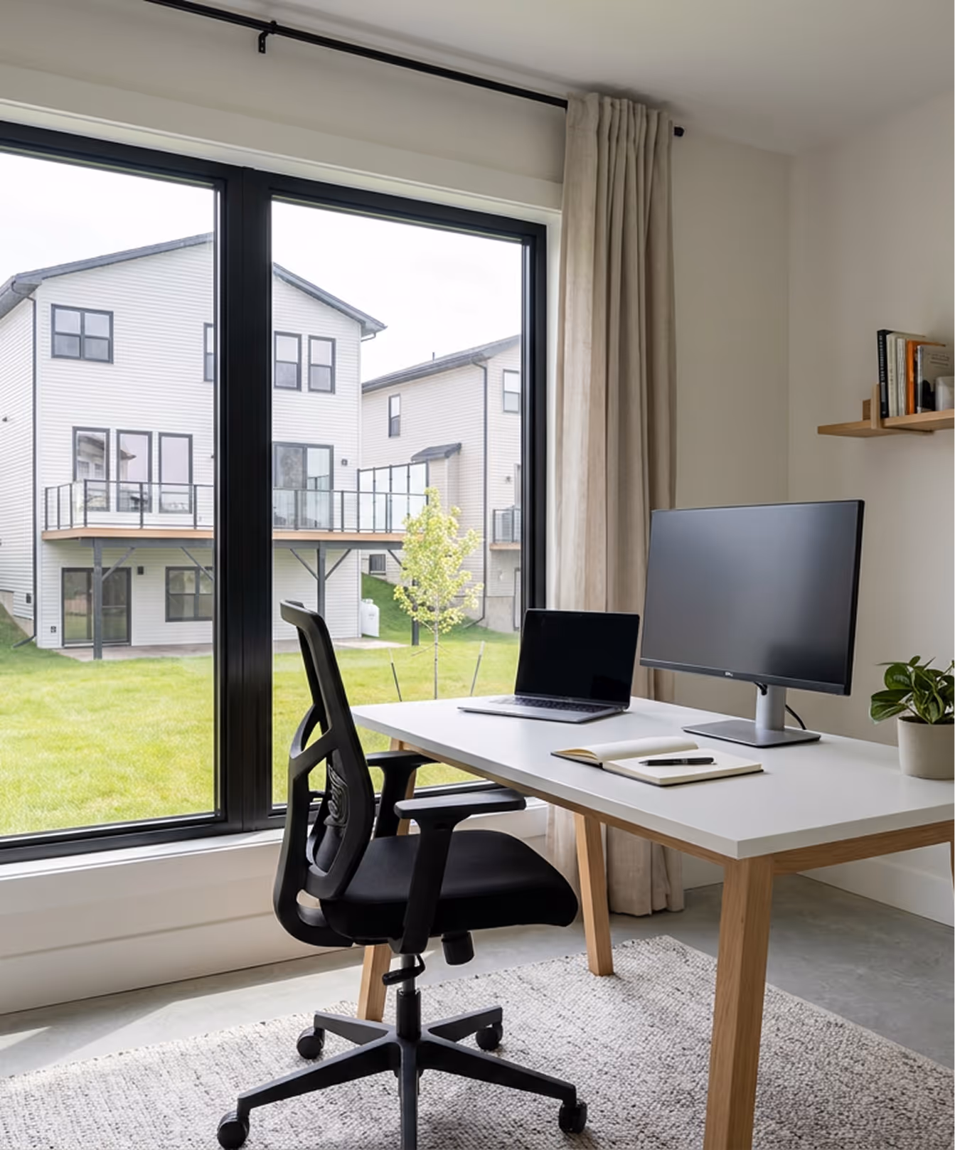 Contemporary backyard office workspace with large glass sliding doors, wooden desk, and view of residential neighborhood in Halifax