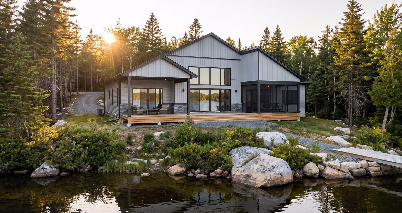 Luxury waterfront home in Halifax with natural stone pond, wooden deck, forest setting, and golden hour lighting